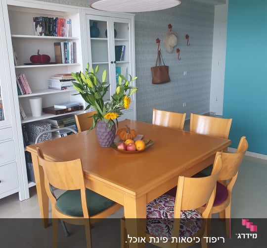 כריות מושב צבעוניות על כיסאות עץ סביב שולחן